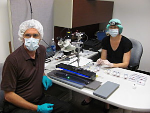 Fig. 1 Scientist Tom Kaye and Carol Abraczinskas use UV light (blue in photo) and a laser (green) to see stains and particles left on Cooper’s tie for accurate sample collection. A forensic vacuum, with 0.8 micron filters, was used for high-density particle collection. FBI Archive - Seattle, WA 2011.